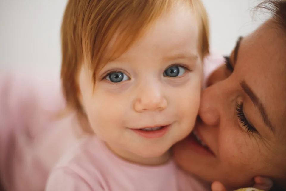 Mother holding her baby close, cheek to cheek