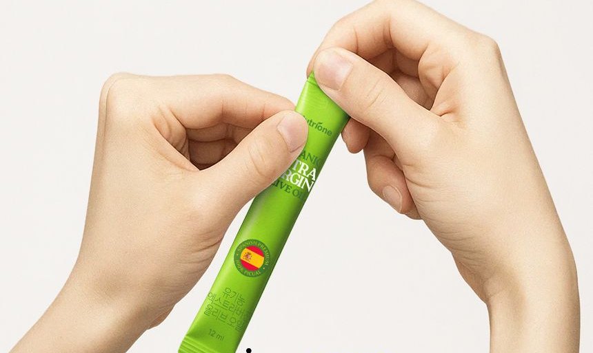 Two hands tearing open an olive oil stick