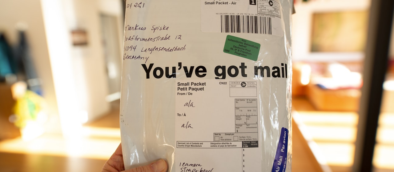 A hand holding a shipping package delivered to a creator's home